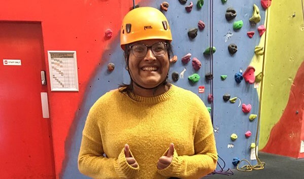Person smiling with thumbs up after rock climbing